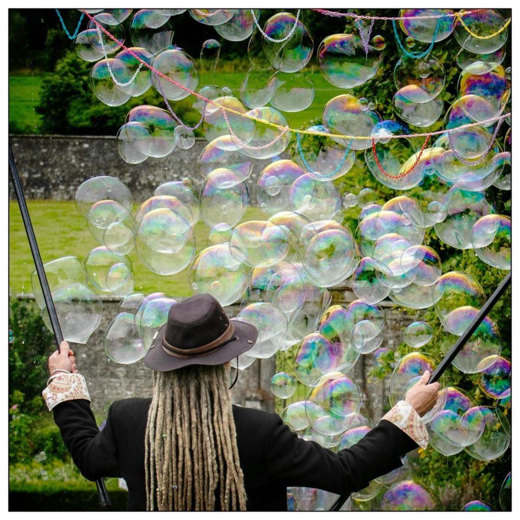 photo of children's entertainer blowing a cloud of bubbles outdoors at a music festival